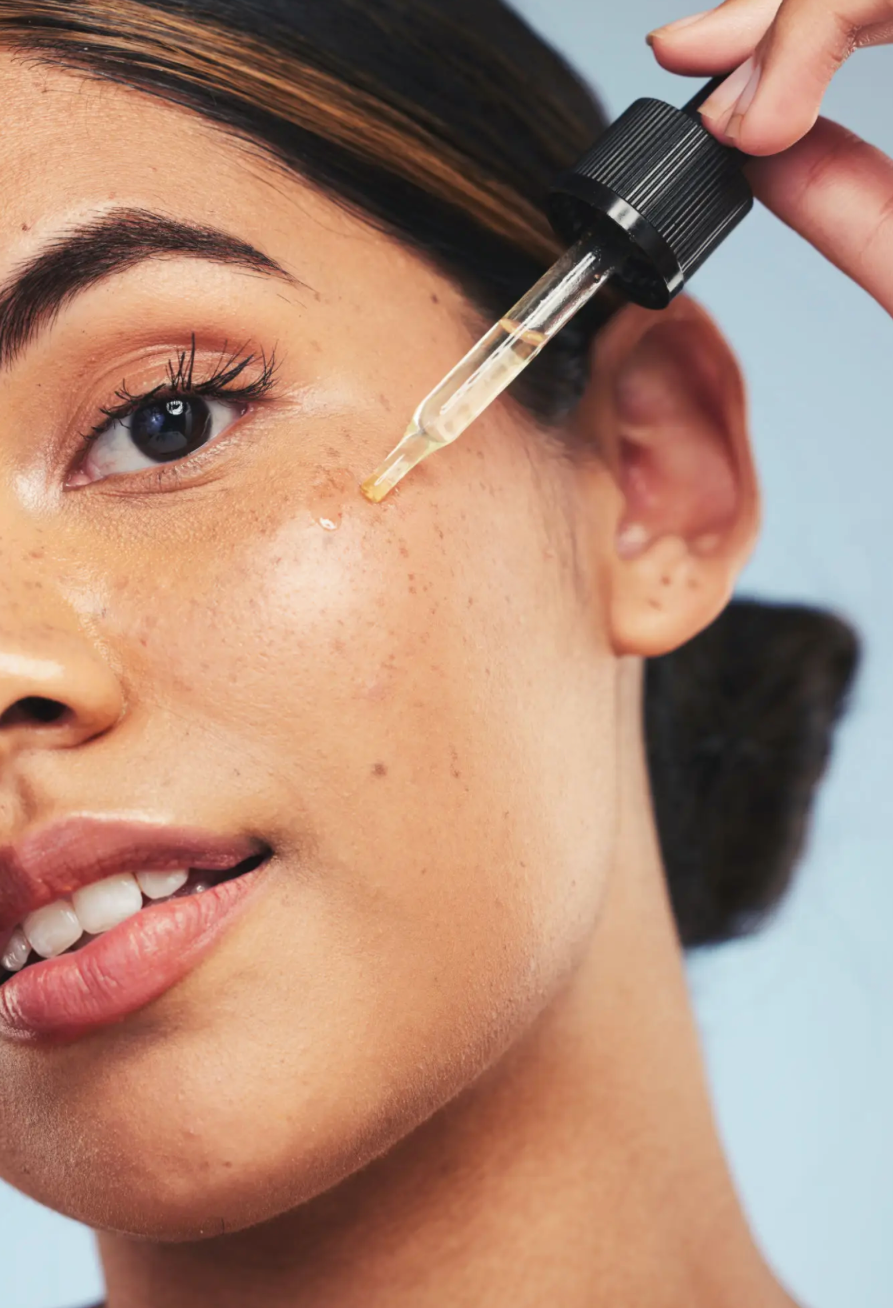 Woman applying facial serum with dropper for skincare.