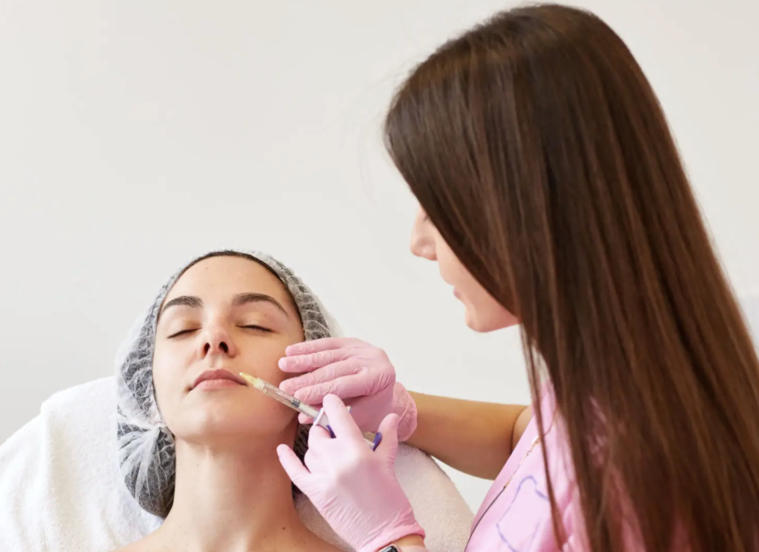 A woman receiving a facial injection from a professional in a clinical setting.