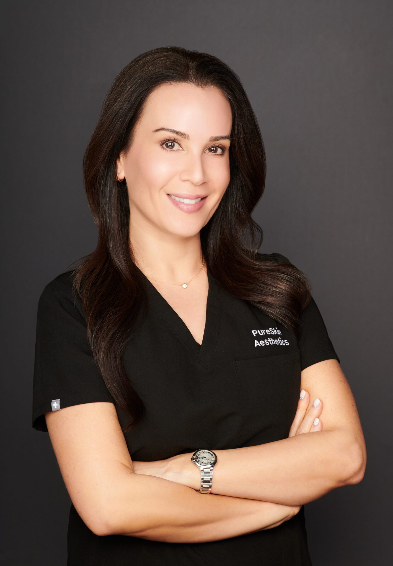 Smiling woman in black medical scrubs posing with arms crossed.