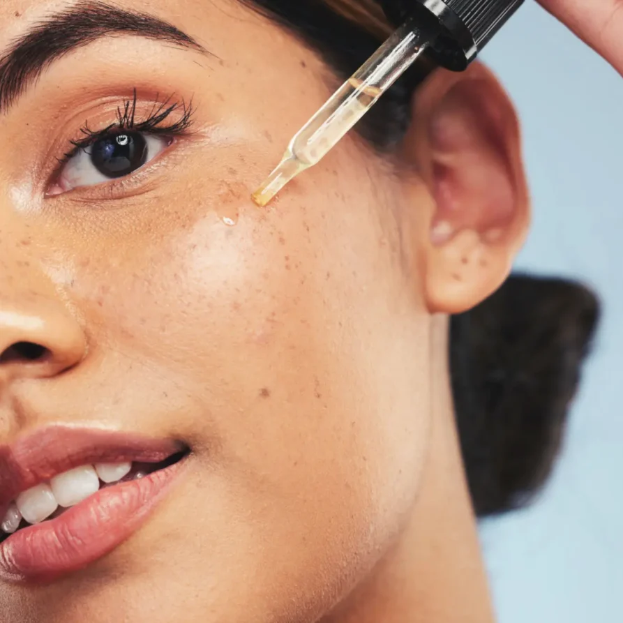Woman applying facial serum with dropper for skincare.